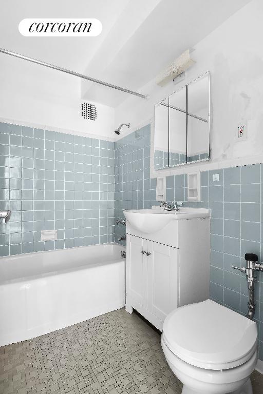 full bathroom with toilet, vanity, tile walls, and shower / bathtub combination