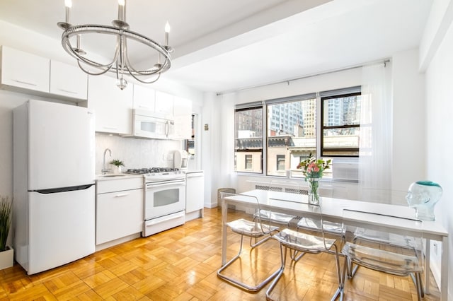 kitchen with sink, a chandelier, white appliances, light parquet flooring, and white cabinets