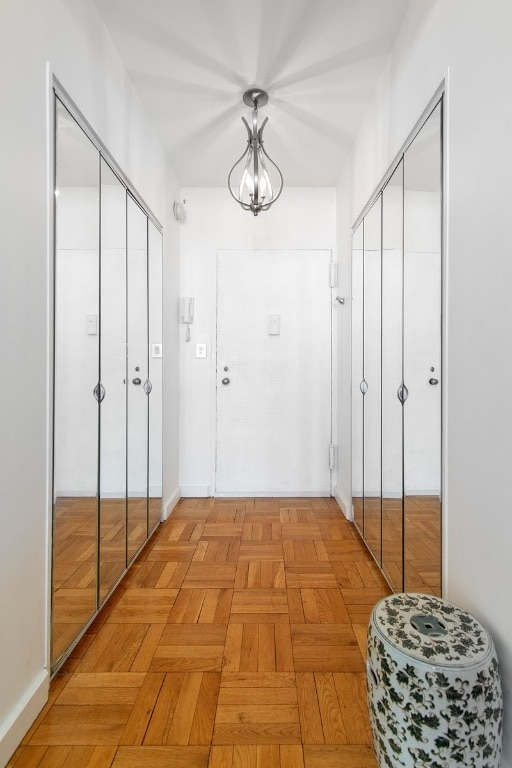 hall with light parquet flooring and a chandelier