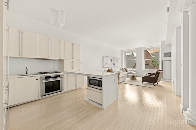 kitchen with a sink, light countertops, open floor plan, and stainless steel appliances