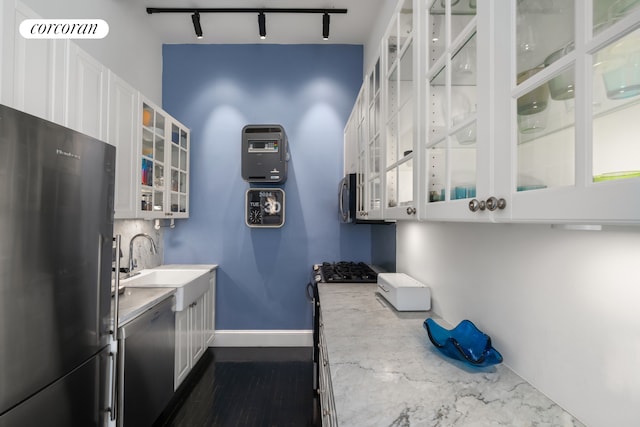 kitchen with track lighting, glass insert cabinets, baseboards, white cabinets, and stainless steel appliances