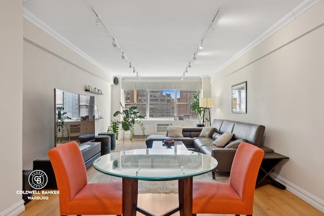 dining area featuring light hardwood / wood-style floors, rail lighting, and ornamental molding