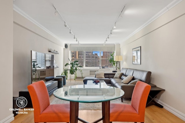 dining area featuring wood finished floors, track lighting, and crown molding