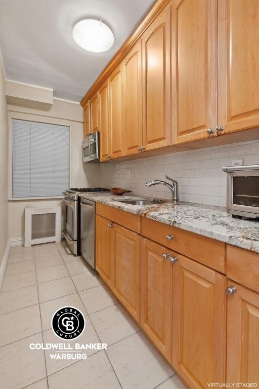 kitchen featuring light stone counters, stainless steel appliances, sink, and backsplash