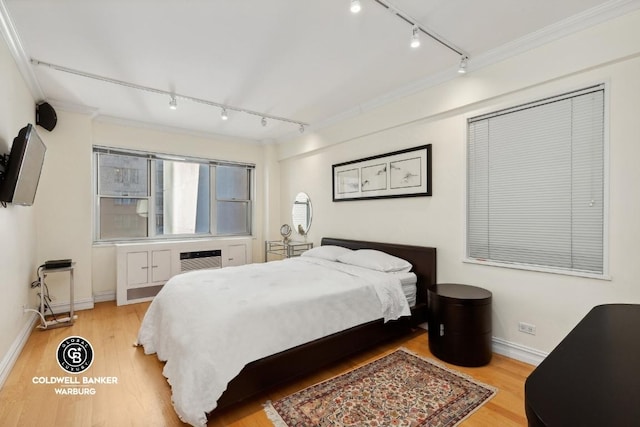 bedroom featuring crown molding, light hardwood / wood-style flooring, rail lighting, and a wall mounted AC