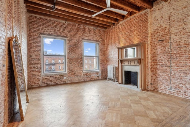 unfurnished living room with a high ceiling, brick wall, and beamed ceiling