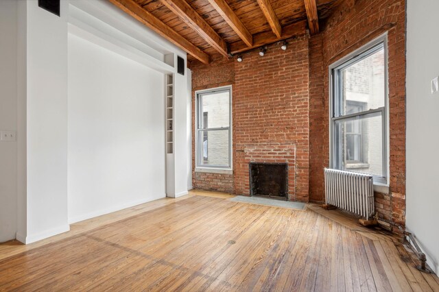 unfurnished living room with beamed ceiling, brick wall, a towering ceiling, and wood ceiling