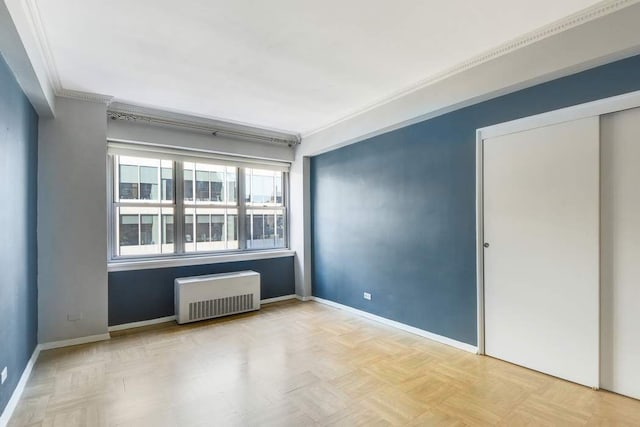 spare room featuring crown molding, light parquet flooring, and radiator heating unit