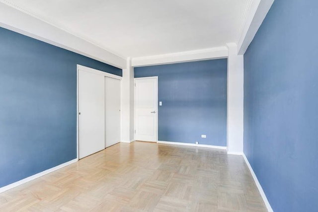 unfurnished bedroom featuring light parquet floors, ornamental molding, and a closet