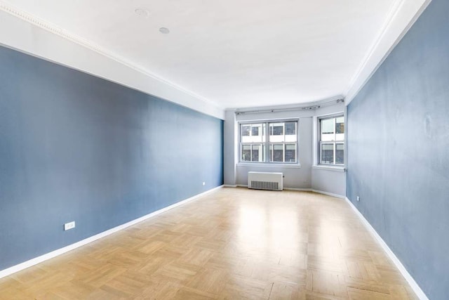 spare room with light parquet floors, radiator heating unit, and crown molding