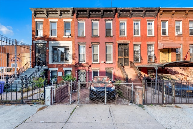 townhome / multi-family property featuring a gate, cooling unit, brick siding, and a fenced front yard