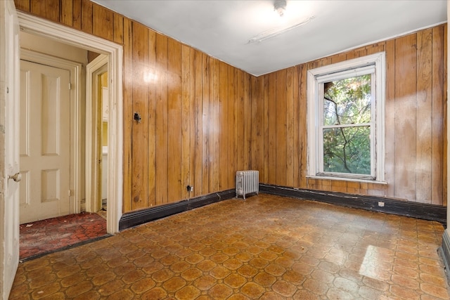 spare room with wooden walls, radiator heating unit, and dark floors