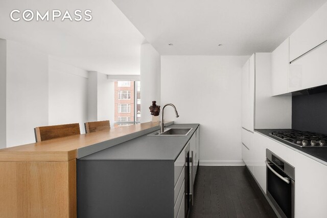 kitchen featuring a breakfast bar, sink, white cabinetry, kitchen peninsula, and stainless steel appliances