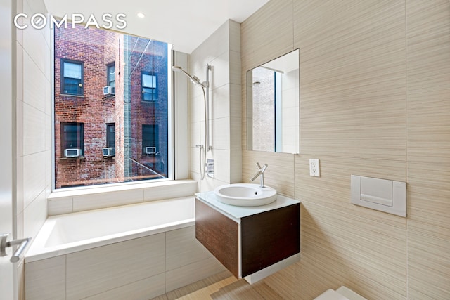 full bath with tiled shower, tile walls, vanity, and tiled tub