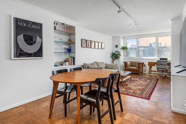 dining space with crown molding, parquet flooring, and track lighting