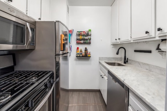 kitchen featuring white cabinetry, sink, light stone counters, and appliances with stainless steel finishes