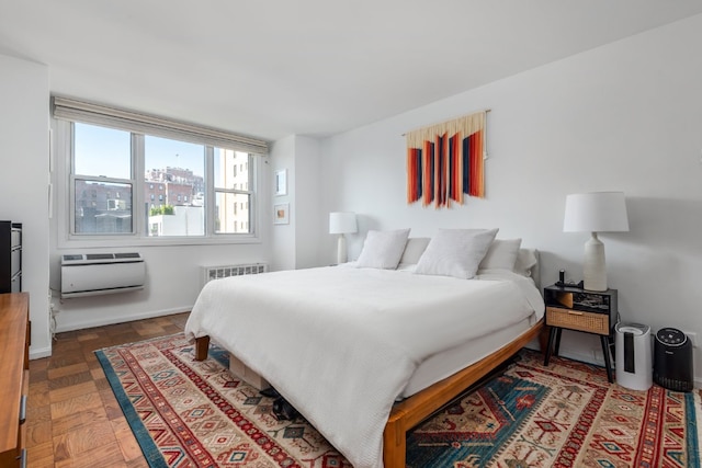 bedroom featuring parquet floors, radiator heating unit, and a wall unit AC