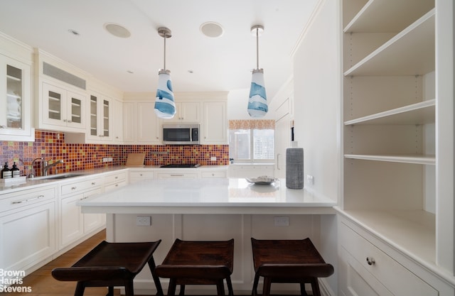 60 E End Ave Unit 24/25A, New York City, NY 10028 - kitchen featuring a sink, a breakfast bar area, white cabinetry, stainless steel microwave, and tasteful backsplash