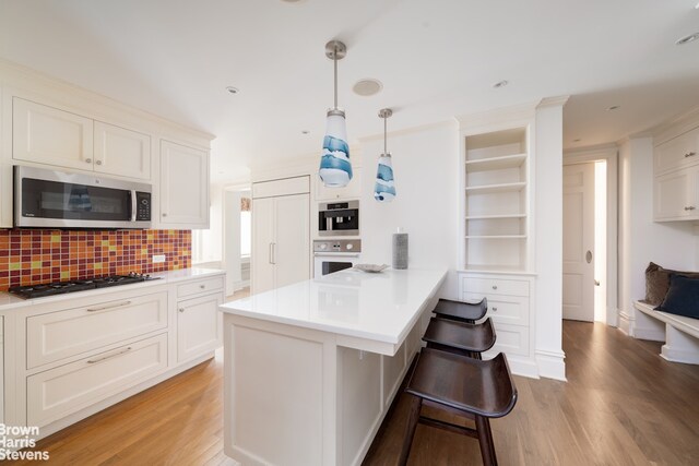 60 E End Ave Unit 24/25A, New York City, NY 10028 - kitchen featuring gas cooktop, a peninsula, light wood finished floors, and stainless steel microwave