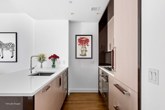 kitchen featuring dark wood-type flooring, stainless steel oven, black gas stovetop, and sink