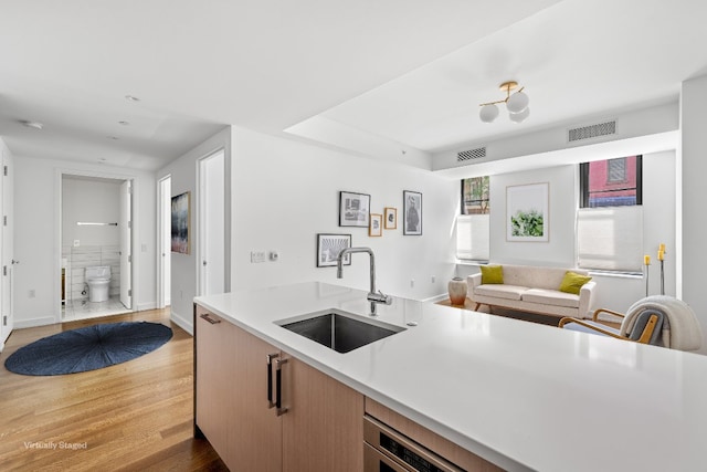 kitchen with sink, light brown cabinets, and hardwood / wood-style flooring