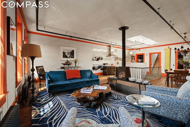 living room with wood-type flooring, crown molding, radiator heating unit, and a skylight