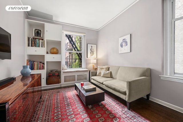 living room with crown molding, baseboards, and wood finished floors