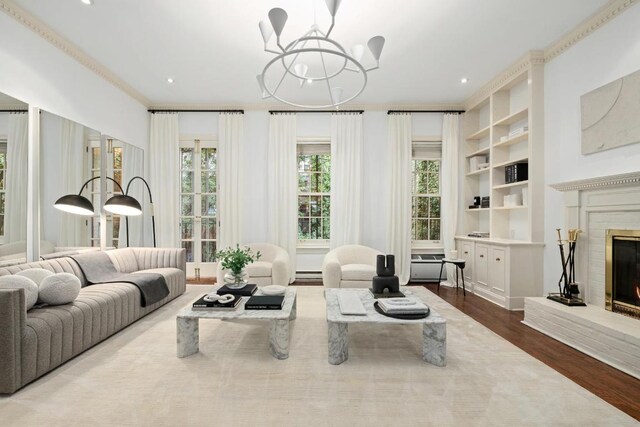 living room featuring a brick fireplace, a healthy amount of sunlight, hardwood / wood-style flooring, and built in shelves