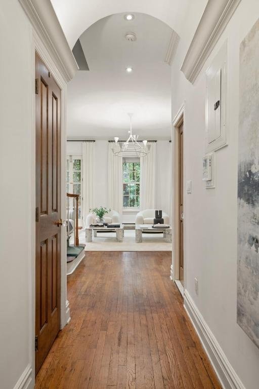 corridor with hardwood / wood-style floors, electric panel, and a chandelier