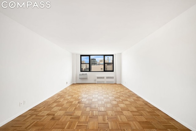 spare room featuring radiator heating unit and light parquet flooring