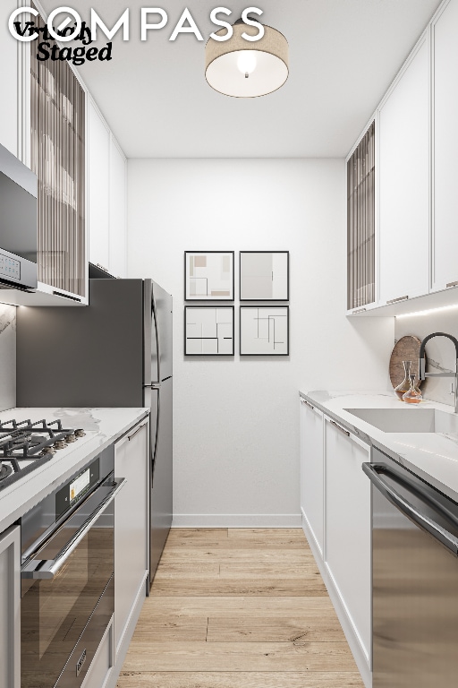 kitchen with appliances with stainless steel finishes, light stone countertops, sink, and white cabinets