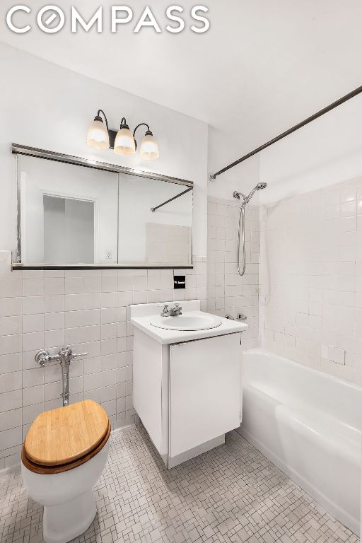 full bathroom with toilet, tiled shower / bath, tile walls, vanity, and tile patterned flooring