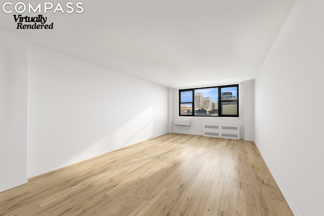 empty room with radiator heating unit and light hardwood / wood-style floors