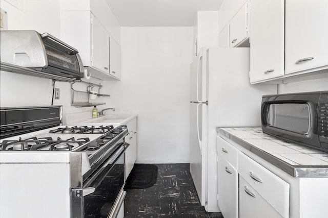 kitchen featuring tile countertops, gas range, white cabinets, and black microwave