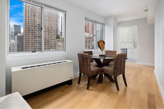 dining area featuring baseboards, light wood-type flooring, and radiator