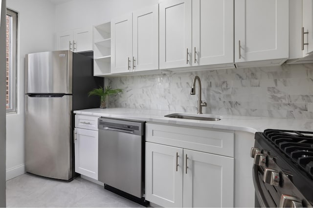 kitchen with a sink, light stone counters, appliances with stainless steel finishes, white cabinetry, and open shelves