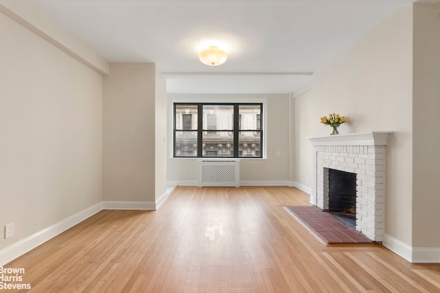 unfurnished living room with radiator, a fireplace, and wood-type flooring