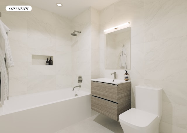 full bathroom featuring tile walls, vanity, tiled shower / bath combo, and toilet