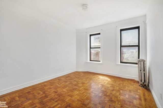 empty room featuring radiator heating unit and parquet flooring