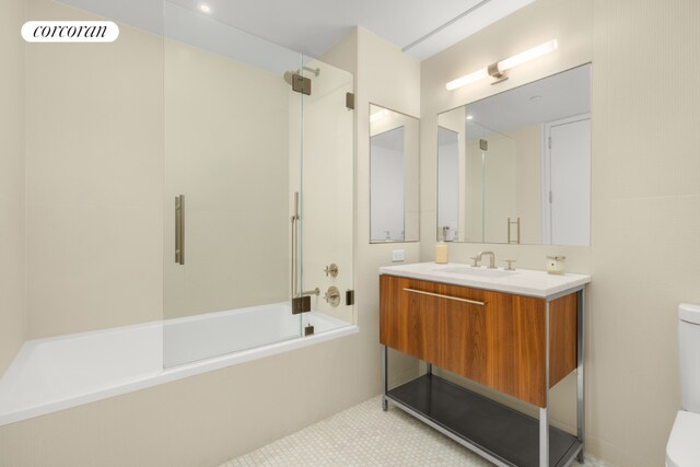 full bathroom featuring toilet, vanity, and bath / shower combo with glass door