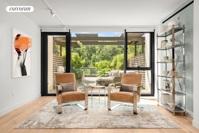 living area with rail lighting, a wall of windows, visible vents, wood finished floors, and baseboards