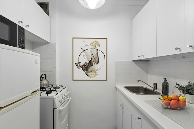 kitchen featuring white appliances, light countertops, tasteful backsplash, and a sink