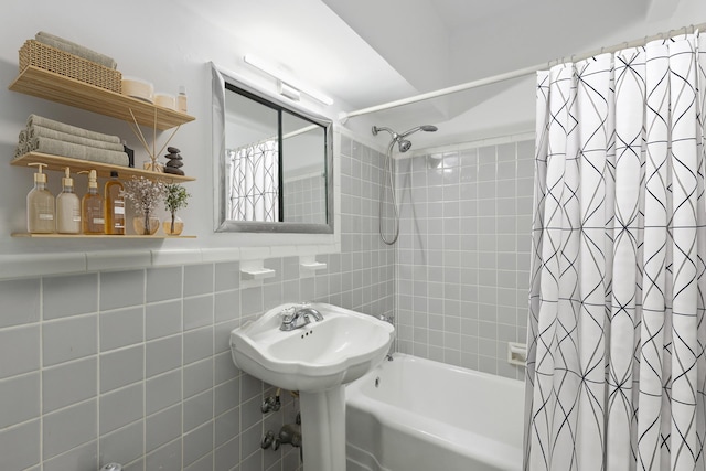 bathroom with a sink, shower / bathtub combination with curtain, and tile walls