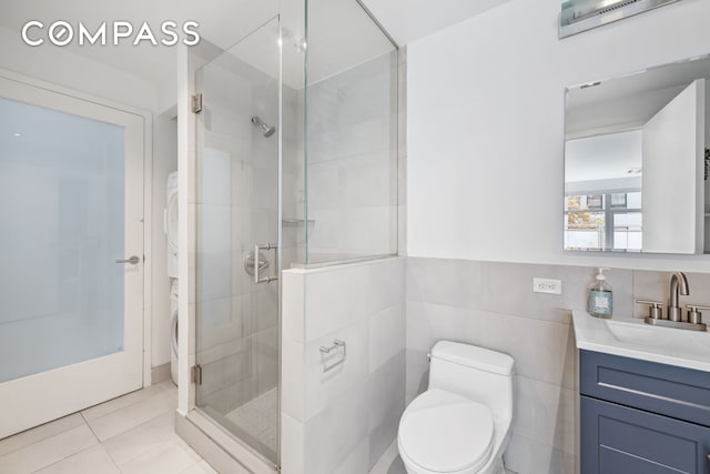 full bath with stacked washer and clothes dryer, toilet, tile patterned flooring, vanity, and a shower stall