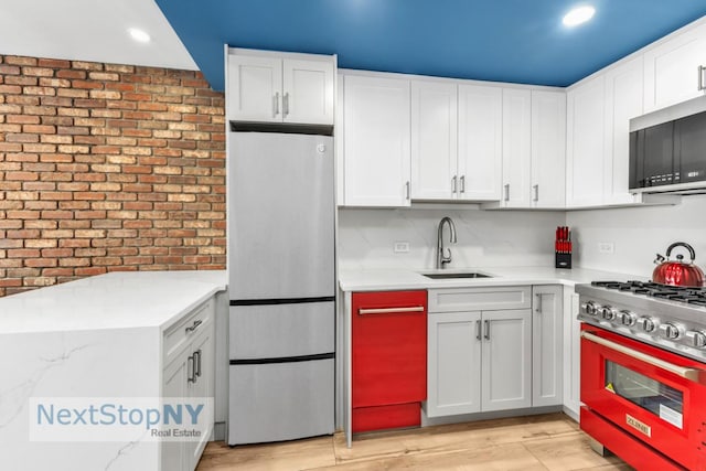 kitchen featuring white cabinetry, range, fridge, and sink