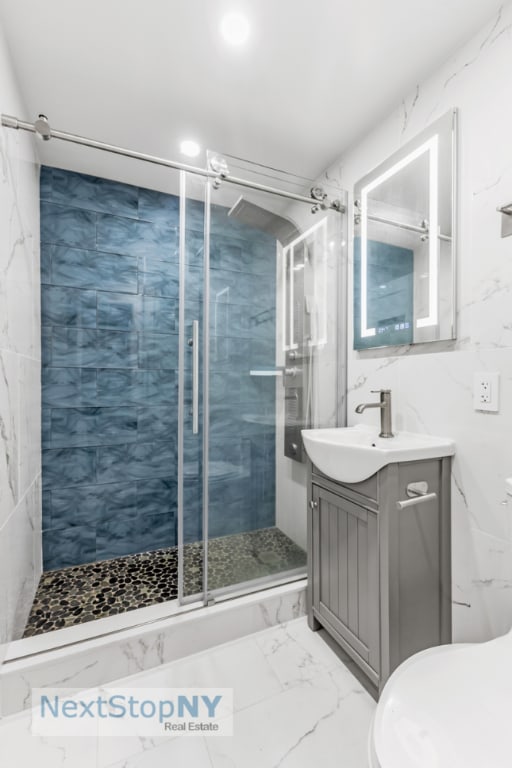 bathroom with a shower with shower door and vanity