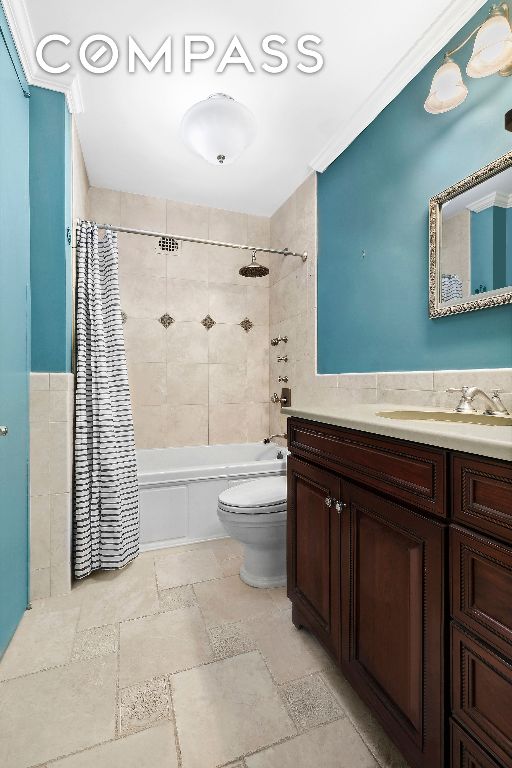 bathroom with toilet, stone tile floors, shower / tub combo, tile walls, and vanity