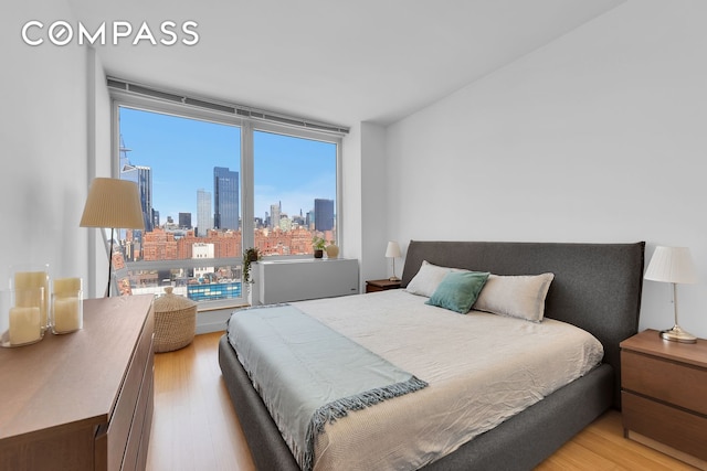 bedroom featuring a view of city and light wood-style floors