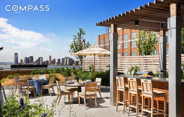 view of patio / terrace featuring a view of city, outdoor dry bar, and outdoor dining area