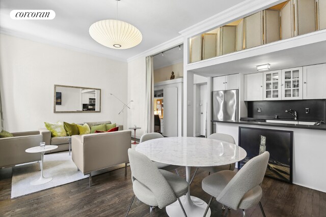 dining area featuring dark hardwood / wood-style flooring, crown molding, and a high ceiling